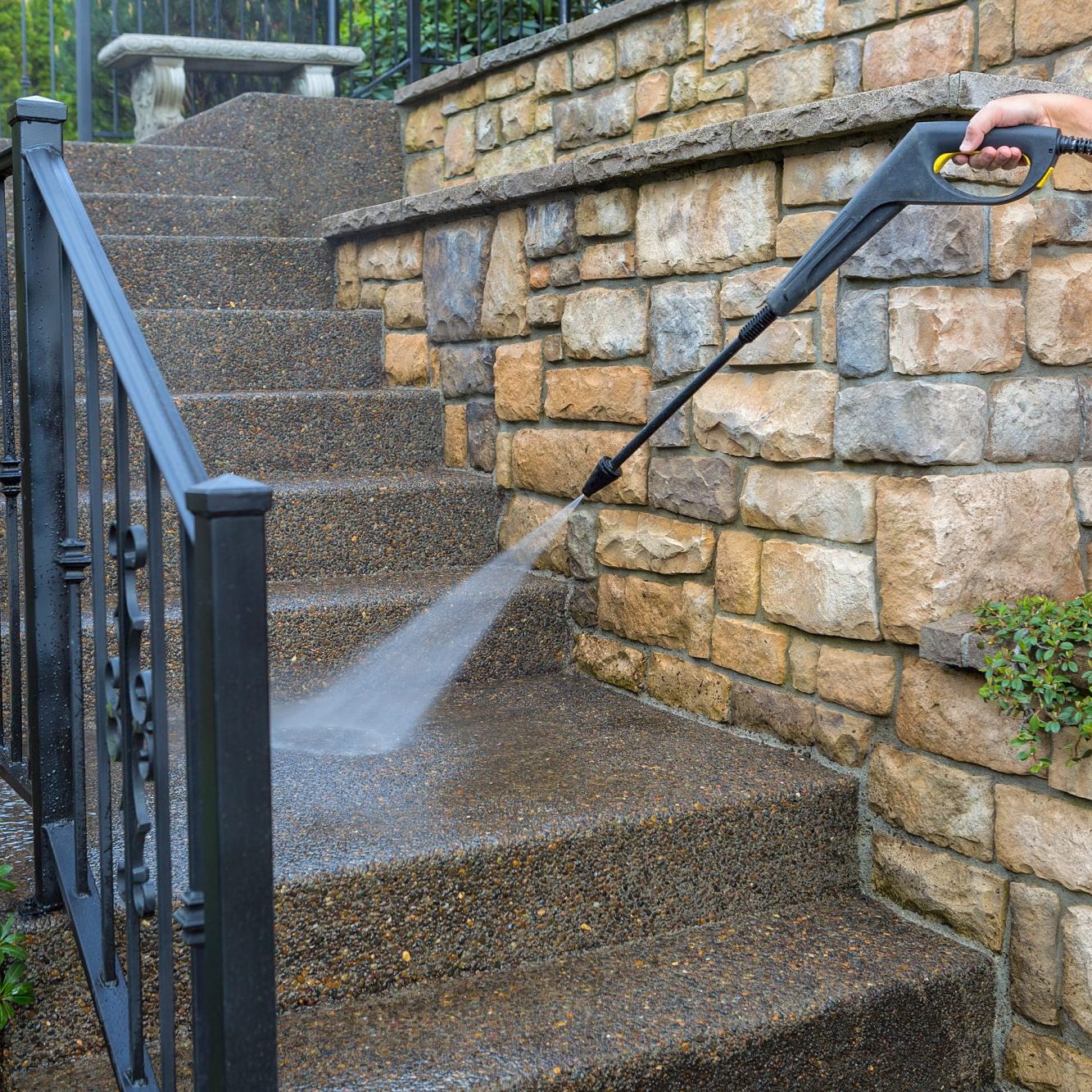 Washing the house front entrance stair steps and stone walls with pressure power washer